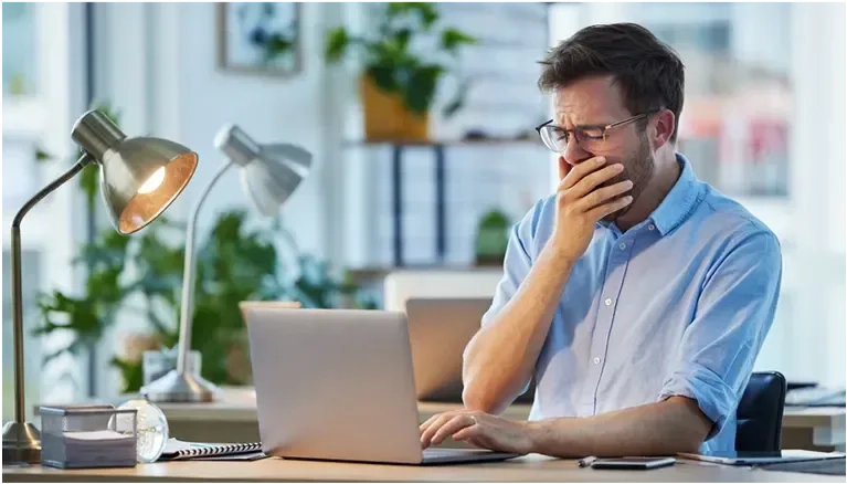 man asleep at his desk, head on hands